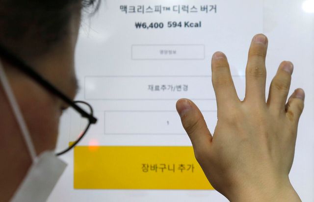 2022년 7월 서울 중구의 한 햄버거점에서 ‘시각장애인권리보장연대의 키오스크 내돈내산 권리찾기 캠페인’에 참가한 한 시각장애인이 버튼을 누르기 위해 화면을 만지고 있다. [사진제공=뉴시스]<br>