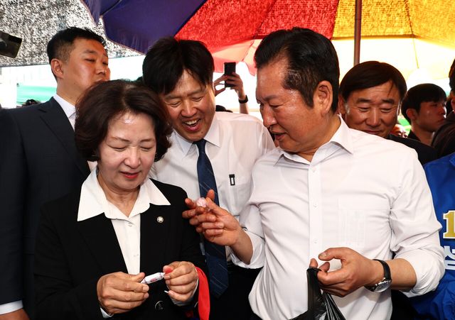 정청래 더불어민주당 대표가 19일 오후 경기 성남시 모란시장 민속5일장에서 김용 전 민주연구원 부원장에게 사탕을 건네고 있다. [사진제공=뉴시스]