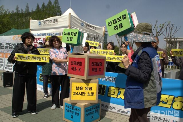 간병노동자들이 21일 국회 앞에서 산재보험 적용과 노동자성 인정을 촉구하며 차별 구조를 상징하는 상자를 부수는 퍼포먼스를 하고 있다. ⓒ투데이신문<br>