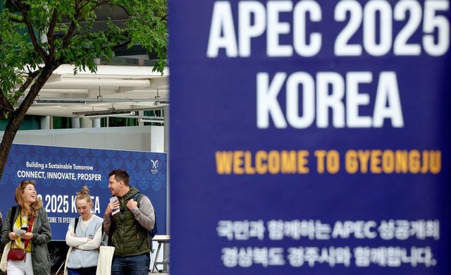 2025 아시아태평양경제협력체(APEC) 현수막 뒤로 지나가는 외국인들. [사진제공=뉴시스]
