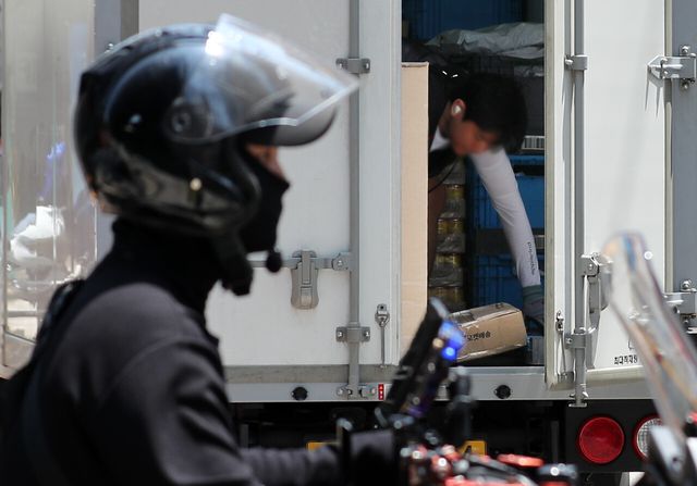 2023년 한 택배기사와 배달기사가 물품을 배달하고 있다. [사진제공=뉴시스]