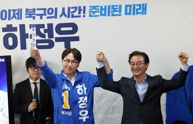 하정우 더불어민주당 부산 북구갑 국회의원 보궐선거 후보가 10일 부산 북구의 한 건물에서 자신의 선거사무소 개소식을 열고 전재수 부산시장 후보로부터 '북구의 미래'라고 적힌 배턴을 넘겨받은 뒤 손을 들어 인사하고 있다. [사진제공=뉴시스]