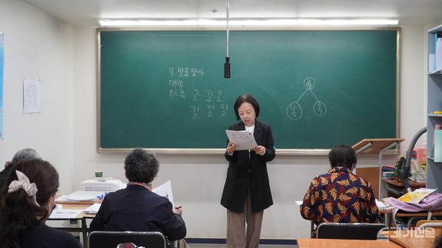 초등학교 반 국어 시간. 김희란 교사와 학생들이 칠판에 적힌 '족', '촉', '쪽' 등의 글자를 소리 내어 읽고 있다.<br>