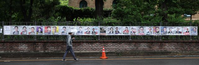지난 21일 서울 종로구 예술가의 집 담장에 부착된 제9회 전국동시지방선거 선거벽보 앞을 한 시민이 지나고 있는 모습. [사진제공=뉴시스]<br>