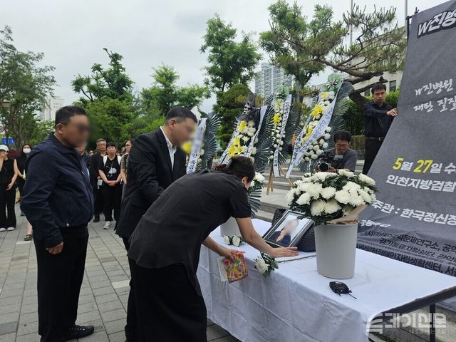 27일 인천지검 부천지청 앞에서 열린 W진병원 격리·강박 사망 사건 추모식에서 고인의 어머니가 영정사진을 쓰다듬고 있는 모습을 유족들이 지켜보고 있다. 좌측부터 고인의 아버지, 남매, 어머니. ⓒ투데이신문<br>