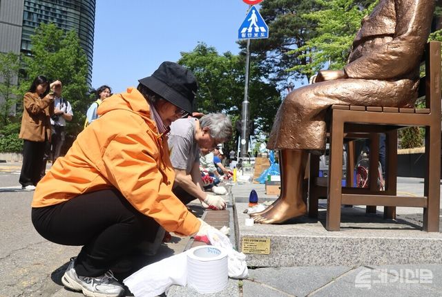 6일 오후 평화디딤돌 자원봉사자들이 평화의 소녀상 앞에 앉아 청소 작업을 진행하고 있다.&nbsp;ⓒ투데이신문