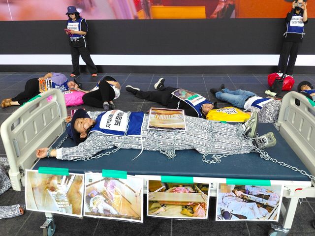 22일 오전 11시 30분 경기도 수원시 영통구 추미애 경기도지사 당선인의 인수위원회인 ‘공정·혁신·포용 경기준비위원회’ 건물 앞에서 정신장애인 억압에 대한 저항을 표현한 병상 전시가 진행되고 있다. [사진제공=한국정신장애인연합회]