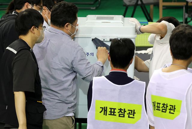 5일 전국동시지방선거 송파구 개표소인 서울 송파구 올림픽공원 핸드볼경기장에서 관계자들이 6·3 지방선거 투표용지 부족 사태를 겪은 잠실7동 제2투표소 투표함 특수봉인지를 뜯고 있다. [사진제공=뉴시스]