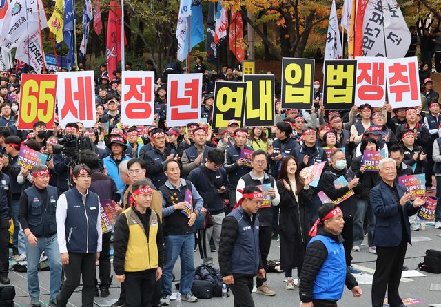 지난해 11월 8일 서울 영등포구 여의대로에서 진행된 ‘2025 한국노총 전국노동자대회’에서 참석자들이 정년 연장 관련 피켓을 들고 있다. [사진제공=뉴시스]