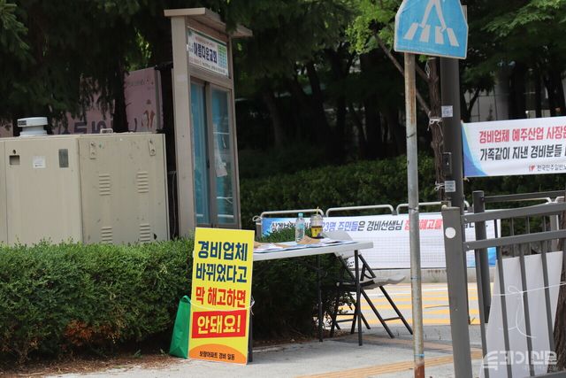 상계보람아파트 입구, 경비노동자 집단해고 반대 서명 테이블 너머 현수막이 걸려 있다. ⓒ투데이신문