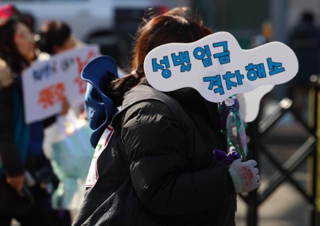 8日下午，值世界妇女节，参加民主劳动总联盟‘继承世界妇女节精神全国劳动者大会’的人员在首尔钟路至大学路方向的街道上游行，手举写有‘消除性别薪酬差距’的标语牌。【图片来源 韩联社】
