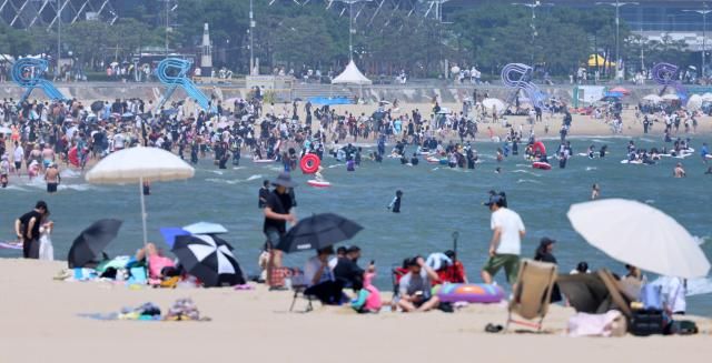29日，釜山部分地区白天气温冲上34摄氏度，在海云台海水浴场，大批游客们尽情戏水消暑。【图片来源 韩联社】
