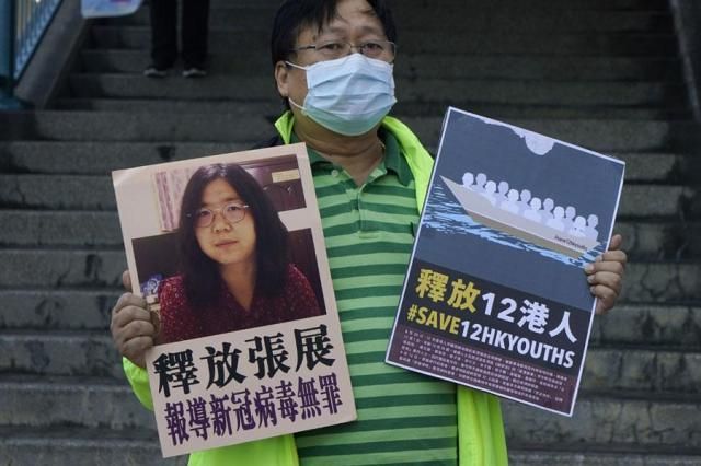 A pro-democracy activist holds placards with a picture of Chinese citizen journalist Zhang Zhan outside the Chinese central governments liaison office in Hong Kong on Dec 28 2020 AP-Yonhap