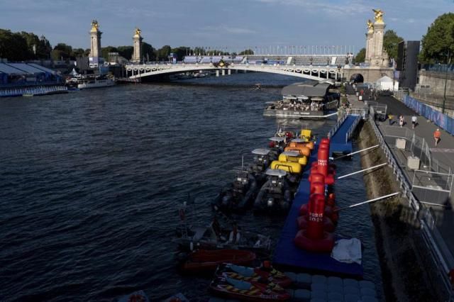 Watercraft and buoys sit along the Seine river as the triathlon event venue on the Pont Alexandre III bridge stands in the background at the Summer Olympics in Paris on July 28 2024 AP-Yonhap