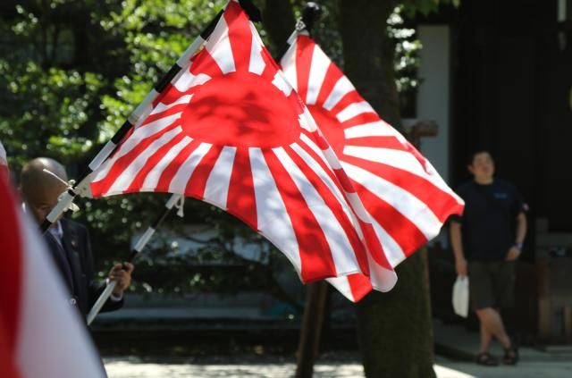 Visitors hold the Rising Sun flag and the Japanese national flag at Tokyos Yasukuni Shrine which enshrines Class-A war criminals on the 80th anniversary of Japans defeat in World War II on Aug 15 2025 YONHAP