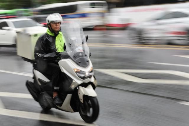 A delivery rider transports food through rain-soaked downtown Seoul reflecting the speed and convenience that have become hallmarks of South Koreas food-delivery culture AJP Yoo Na-hyun