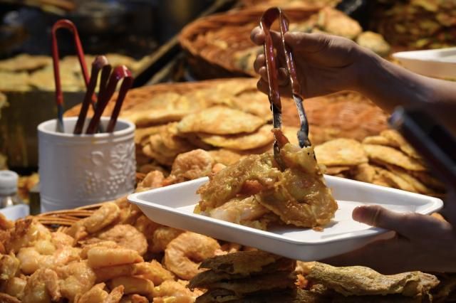 Fresh off the pan: crispy fried shrimp and seafood pancakes being plated with tongs at a street food stall inside Eunma Market on Sept 25. AJP Joonha Yoo