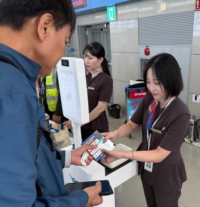 カンボジア行き航空機搭乗ゲート前で案内文を配布する場面写真法務部