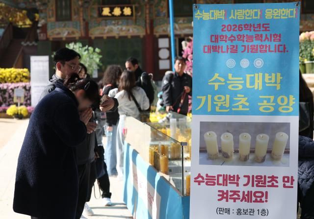 2026学年度の大学修学能力試験の修能を控えた9日、ソウル鍾路区の曹渓寺に設けられた菜入りの菜入り幸福祈願希望のろうそく供養台で、ある市民が両手を合わせている 写真連合ニュース