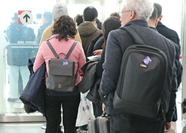 BX146편 탑승객들이 휴대 수하물 내 배터리 소지 유무 확인과 배터리 선반 보관 금지 안내를 받은 후 NO BATTERY INSIDE 스티커를 부착해 탑승하고 있다. [사진=에어부산]