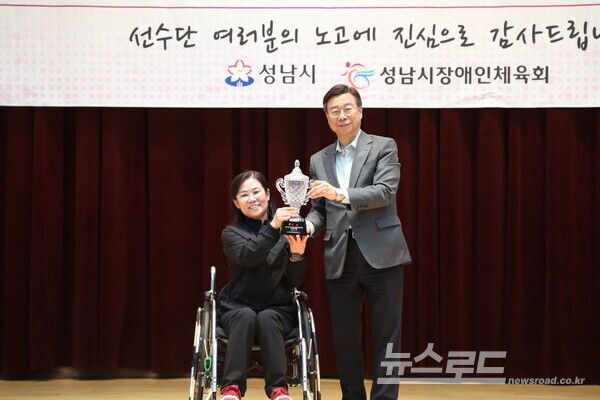 신상진 성남시장이 제15회 경기도장애인체육대회 출전선수단 해단식에 참석해 댄스스포츠 종목에서 4관왕을 차지한 박경하(왼쪽) 선수에게 우승컵을 전달받으며 기념촬영을 하고 있다./사진=성남시