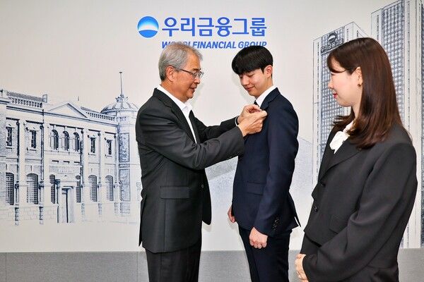 우리금융그룹 임종룡 회장이 그룹의 새 가족이 된 동양생명·ABL생명 직원에게 디지털 선도의 의미가 담긴 새로운 그룹 보조휘장을 달아주고 있다.