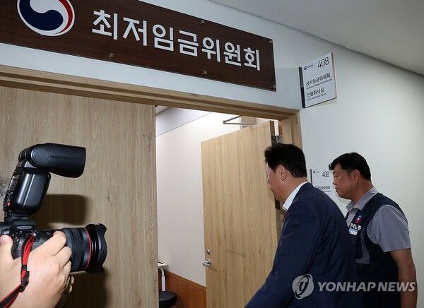 최저임금위원회 사용자위원인 류기정 한국경영자총협회 전무(왼쪽)와 근로자위원 류기섭 한국노총 사무총장이 10일 정부세종청사에서 열린 최저임금위원회 제12차 전원회의에서 민주노총 위원들이 심의를 거부한 채 퇴장해 회의가 정회된 후 밖에서 얘기를 나누고 들어오고 있다./연합뉴스