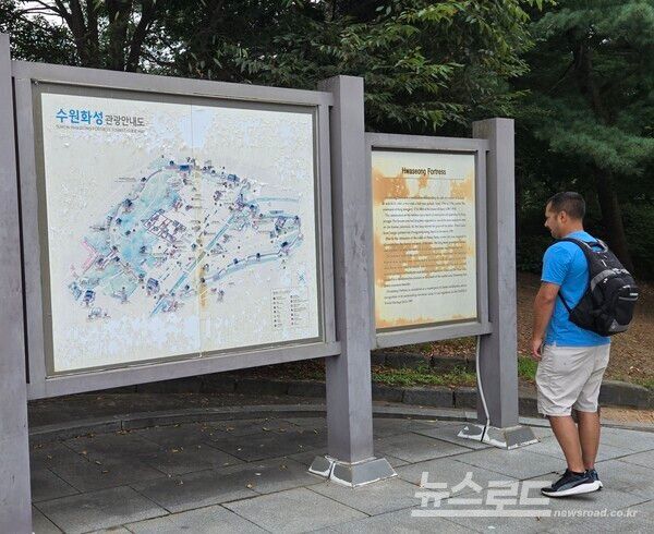 수원화성을 찾은 외국인 관관객이 빛바랜 안내판을 보고 있는 모습/사진=경기도일간기자단