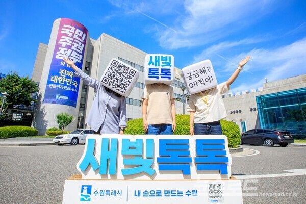 수원시 관계자들이 수원시청 청사 앞에서 새빛톡톡을 홍보하는 사진을 찍고 있다./사진=수원시