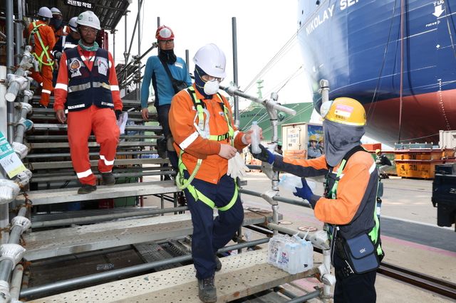 한화오션 안전관리자가 찾아가는 얼음생수 활동으로 오후 쉬는 시간 휴식을 위해 하선하는 작업자들에게 얼음 생수를 전달하고 있다.