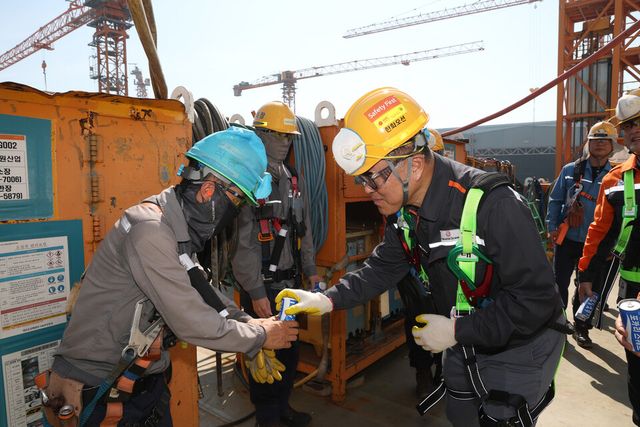 한화오션 김희철 대표이사(오른쪽)가 건조 중인 LNG선박 위에서 근로자들에게 시원한 음료를 건네고 있다.