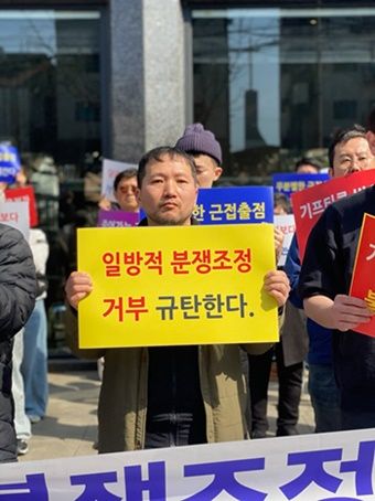 굽네치킨 가맹점주가 기자회견에 참여해 '일방적 분쟁조정 거부 규탄한다'라는 글귀가 적힌 팻말을 들고 있다. [사진=전국가맹점주협의회 제공]
