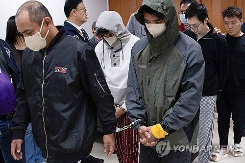 (마닐라 AFP=연합뉴스) 25일(현지시간) 필리핀 마닐라의 필리핀 경찰청 청사에서 경찰이 검거한 중국인 2명 등 간첩 일당을 데리고 이동하고 있다. 2025.02.26 / 사진 = 연합뉴스