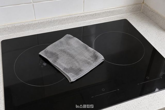 미온수에 적신 극세사 걸레를 식은 인덕션 상판의 작은 자국 위에 올려 둔 모습 / 기사 이해를 돕기 위한 생성형 이미지