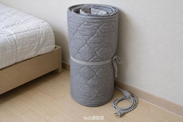 느슨하게 만 전기장판을 벽에 세우고 코드도 눌리지 않게 둔 모습 / 기사 이해를 돕기 위한 생성형 이미지