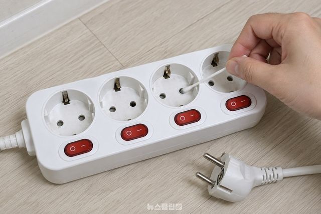 면봉 끝을 멀티탭 구멍 안에 넣어 안쪽 벽을 따라 돌리며 긁고 있다. / 기사 이해를 돕기 위한 생성형 이미지