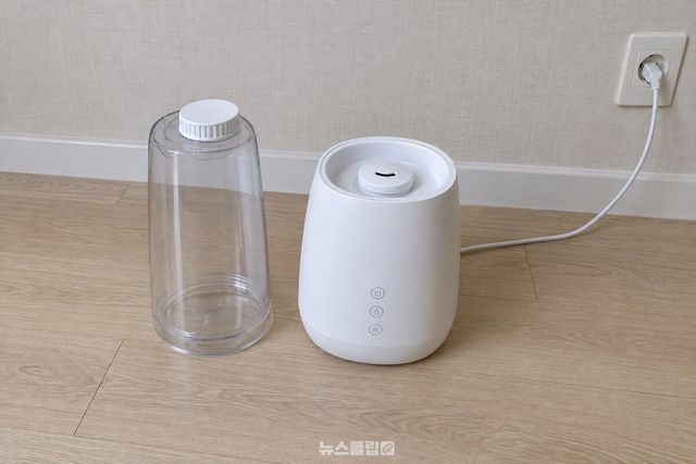 거실 바닥에 놓인 초음파 가습기 본체와 그 옆에 세워 둔 투명 물통. / 기사 이해를 돕기 위한 생성형 이미지