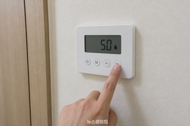 온도조절기의 화살표 버튼을 손가락으로 눌러 온수 설정을 50으로 내리고 있다. / 기사 이해를 돕기 위한 생성형 이미지