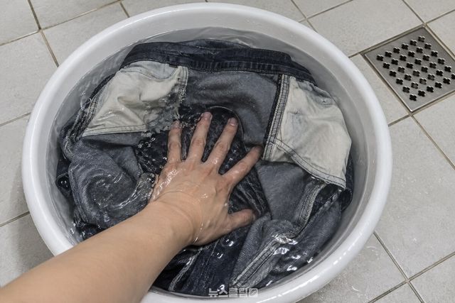 지퍼와 단추를 잠그고 뒤집은 청바지를 손바닥으로 눌러 물속에 완전히 잠기게 하는 모습. / 기사 이해를 돕기 위한 생성형 이미지
