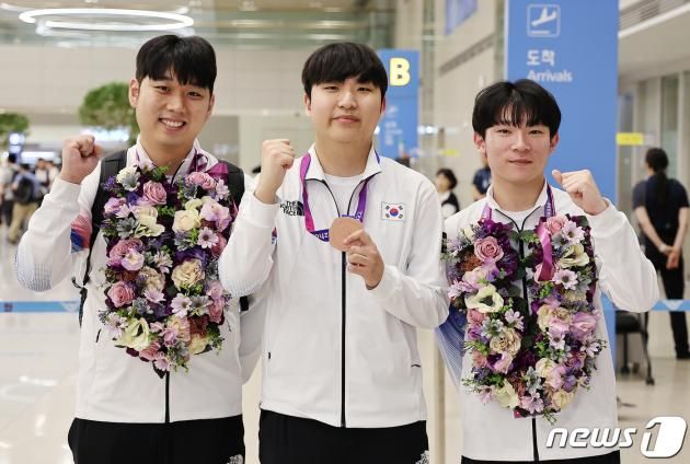 항저우 아시안게임 e스포츠 ‘FC 온라인’ 대표팀의 신보석 감독(왼쪽부터), 동메달을 획득한 곽준혁, 박기영이 29일 오후 인천국제공항 제2터미널을 통해 귀국한 뒤 기념 촬영을 하고 있다. 곽준혁은 지난 27일 중국 항저우 e스포츠센터에서 열린 FC온라인 패자조 결승에서 태국 파타나삭에게 1-2로 패배해 동메달을 획득했다. 이는 대한민국의 첫 번째 e스포츠 메달이다. 2023.9.29/뉴스1 ⓒ News1 김진환 기자