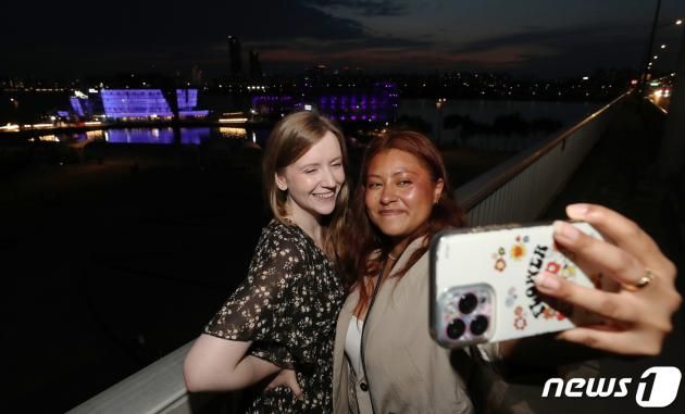 12일 오후 방탄소년단(BTS) 데뷔 10주년을 맞이해 ARMY 상징색인 보랏빛 조명을 밝히고 있는 서울 한강 세빛섬에서 BTS팬인 아미들이 기념사진을 찍고 있다. 2023.6.12/뉴스1 ⓒ News1 박세연 기자