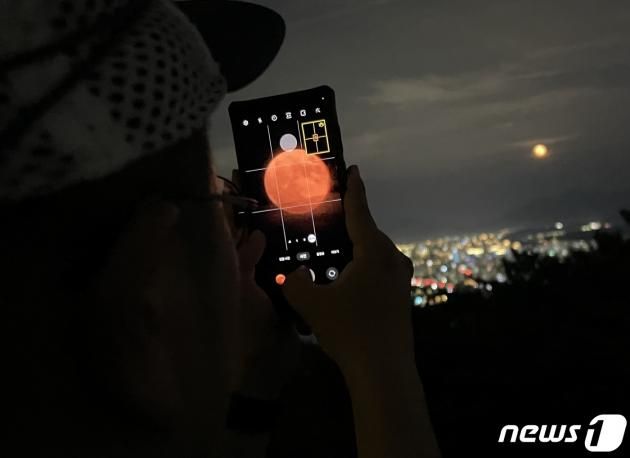 31일 저녁 서울 광진구 아차산을 찾은 등산객이 스마트폰 카메라로 ‘슈퍼 블루문’을 담고 있다. 슈퍼 블루문은 달이 공전 궤도에서 지구와 가장 가까운 지점에 도달할 때 관측할 수 있는 슈퍼문과 같은 달 안에 두 번째로 뜨는 보름달을 가리키는 블루문을 합친 말이다. 2023.8.31/뉴스1 ⓒ News1 오대일 기자