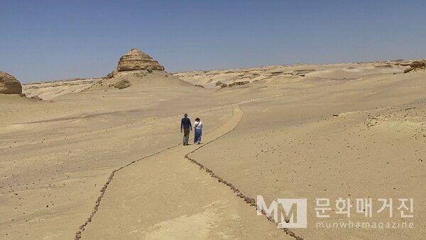 ▲ 끝없이 펼쳐진 파윰의 와디 히탄 사막 길을 두 사람이 걷고 있다. 한때 바다였던 이 땅은 이제 고요한 모래의 파도 위로 인간의 발자국만 남는다 / 사진: 한민광 제공