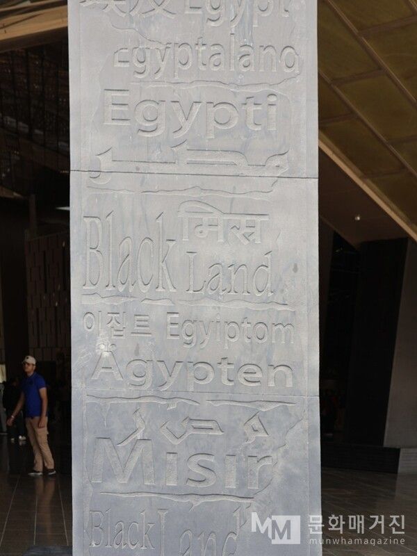 ▲ GEM 입구에 세워진 '언어 기둥'에는 세계 여러 나라의 언어로 적힌 '이집트(Egypt)'라는 이름이 새겨져 있다. 그중 한국어 '이집트'가 또렷하게 포함되어 있어 이 박물관이 지향하는 국제성과 개방성을 상징적으로 보여 준다 / 사진: 한민광 제공