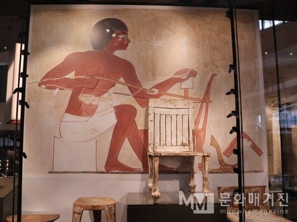 ▲ 도구를 사용하여 정밀한 작업에 몰두하는 장인의 벽화와 그 앞에 놓인 실제 의자는 이집트 문명을 일구어낸 실질적인 주인공들의 노동 가치와 헌신을 증명한다 / 사진: 한민광 제공