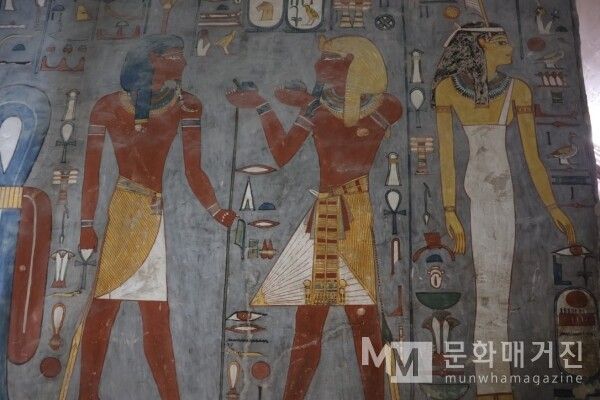 ▲ 고대 이집트의 벽화로, 신과 파라오 그리고 그 곁을 지키는 여왕의 모습을 묘사하고 있다. 화려한 장신구와 의복을 갖춘 인물들의 배치를 통해 당시 왕실 여성의 높은 지위와 종교적 위상을 시각적으로 보여준다 / 사진: 한민광 제공