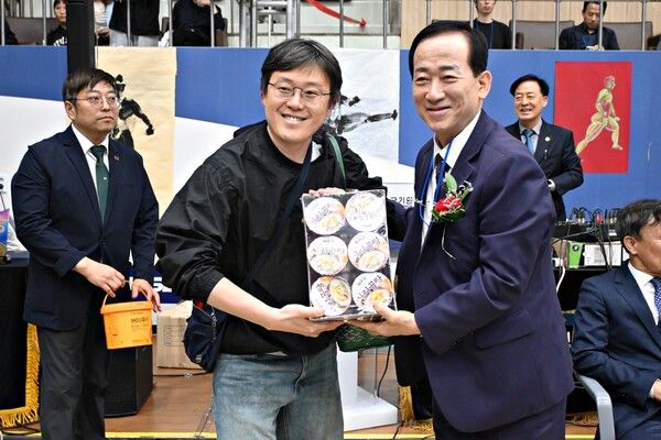오현득 국제태권도연구원장이 경품추첨에 당첨된 학부모에게 경품 샘플을 제공하고 있다/사진 세계어린이태권도연맹 제공