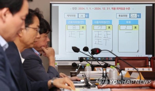 19일 새벽 세종시 정부세종청사 최저임금위원회 회의실 모니터에 표결 결과가 게시되어 있다. 박준식 위원장(왼쪽 두번째)을 포함한 공익위원들이 회의실에 자리하고 있다. (사진=연합뉴스)