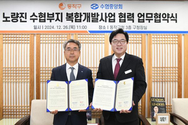 김기성 수협중앙회 지도경제대표이사(왼쪽)와 박일하 동작구청장이 지난 26일 노량진 일대를 서울 랜드마크로 조성하기로 약속하는 ‘노량진 수협부지 복합개발사업 협력’ 업무협약을 체결한 뒤 협약서를 들고 기념촬영을 하고 있다.(사진=수협중앙회)