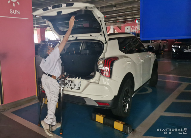 하반신 장애인이 휠체어에 앉았을 때보다 상대적으로 키가 큰 목발 장애인도 차량 트렁크를 닫지 못하고 있다. 사진은 목발 장애인 이성수 씨(56)가 본인 소유 차량 '티볼리' 트렁크를 닫지 못하고 있는 모습. 소형 SUV인 해당 차량도 장애인 운전자는 트렁크를 사용하지 못하는 경우가 많다. /여성경제신문